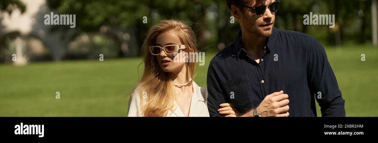 Una bella giovane coppia, elegantemente vestita, che cammina insieme in un parco verde. Foto Stock