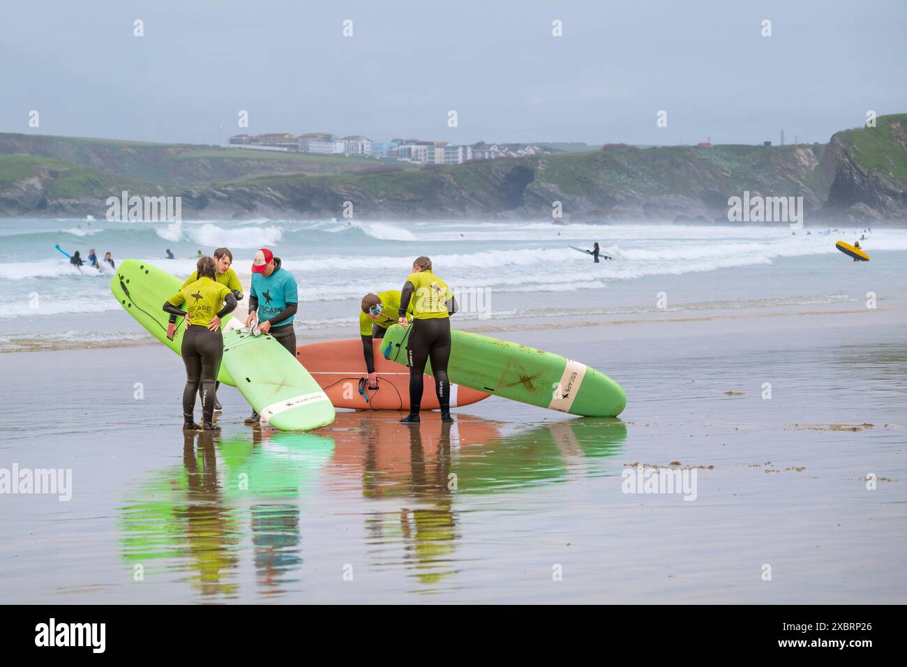 I principianti della Escape Surf School terminano una lezione con il loro insegnante di surf sulla spiaggia di Towan a Newquay in Cornovaglia nel Regno Unito. Foto Stock