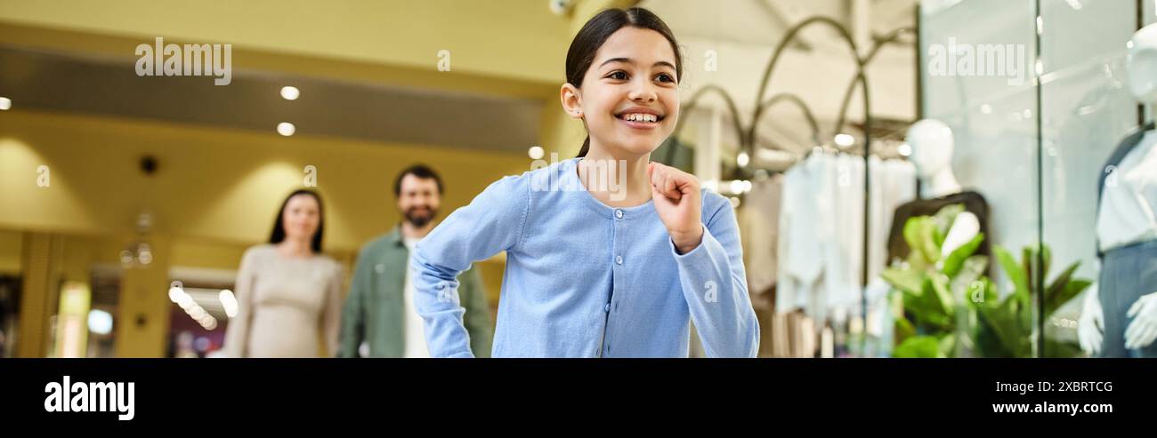 Un bambino corre energicamente attraverso un vivace centro commerciale pieno di negozi e acquirenti. Foto Stock