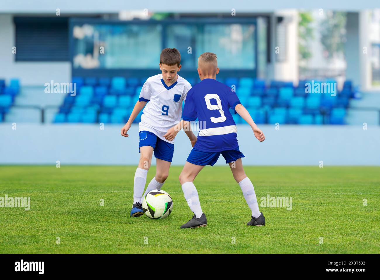 Un giovane giocatore di calcio dribbla abilmente davanti a un avversario in una partita tra squadre giovanili Foto Stock