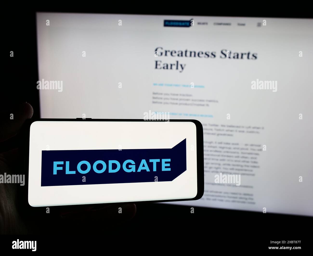 Persona che possiede uno smartphone con il logo della società di venture capital statunitense Floodgate Fund LP davanti al sito Web. Mettere a fuoco il display del telefono. Foto Stock