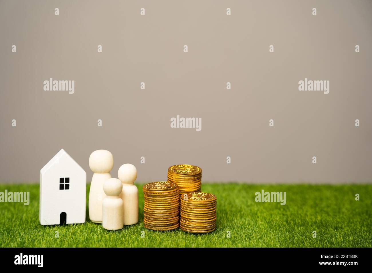 Le miniature della famiglia si trovano vicino alla casa e alle monete. Il concetto di budget familiare, prestiti ipotecari e denaro in famiglia. Immobiliare AN Foto Stock