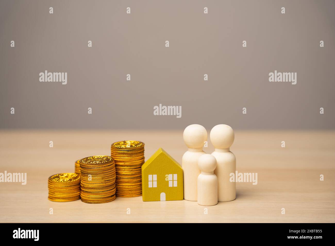 Le miniature della famiglia si trovano vicino alla casa e alle monete. Il concetto di budget familiare, prestiti ipotecari e denaro in famiglia. Immobiliare AN Foto Stock