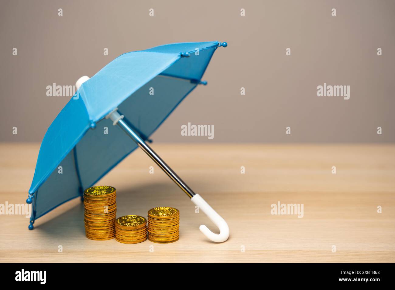 Le monete si trovano sotto un ombrello blu. Concetto di assicurazione contro il rischio finanziario. Investimenti, depositi e prestiti. Rischi e transazioni monetarie. Contr. Assicurazione Foto Stock