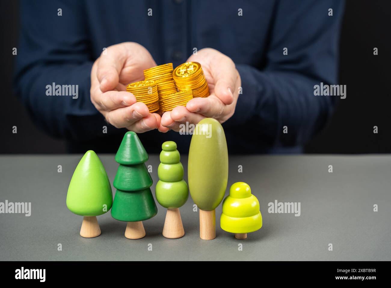 Uomo d'affari che tiene monete sugli alberi. Obbligazioni verdi. Il concetto di investimento nello sviluppo dei parchi cittadini e nella piantagione di piante e piante. Foto Stock