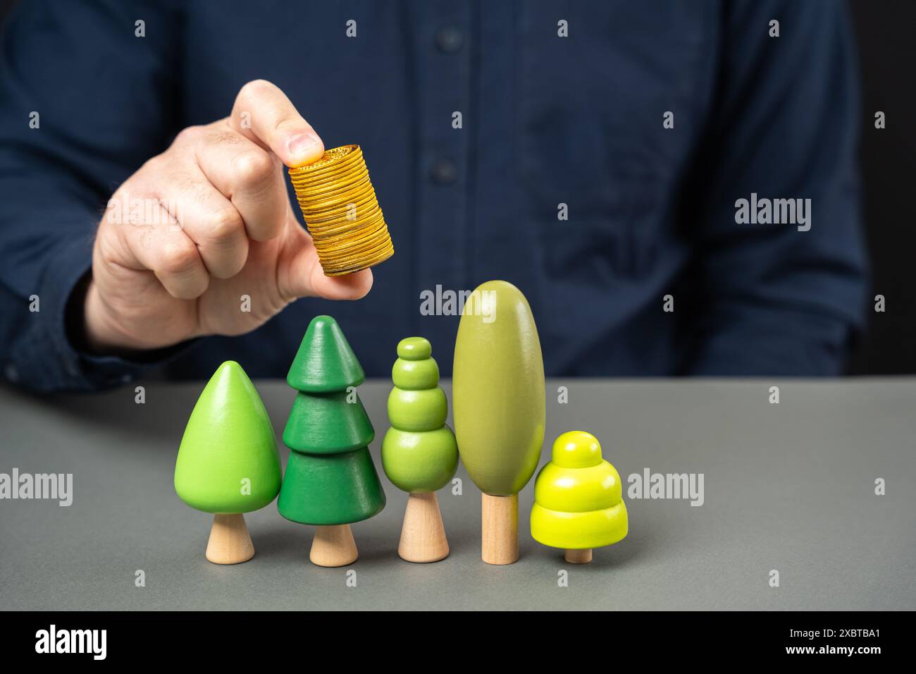 Uomo d'affari che tiene monete sugli alberi. Obbligazioni verdi. Il concetto di investimento nello sviluppo dei parchi cittadini e nella piantagione di piante e piante. Foto Stock