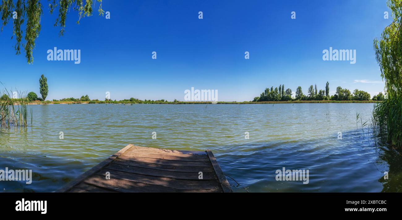 Vista dal trampolino di legno, ponte per immersioni, pesca vicino al lago e allo stagno. Paesaggio di laghetti blu Foto Stock