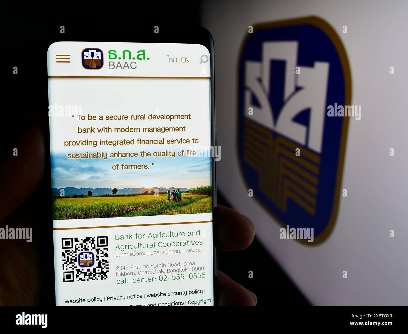 Persona che detiene un cellulare con pagina web della Banca per l’agricoltura e le cooperative agricole (BAAC) con logo. Messa a fuoco al centro del display del telefono. Foto Stock