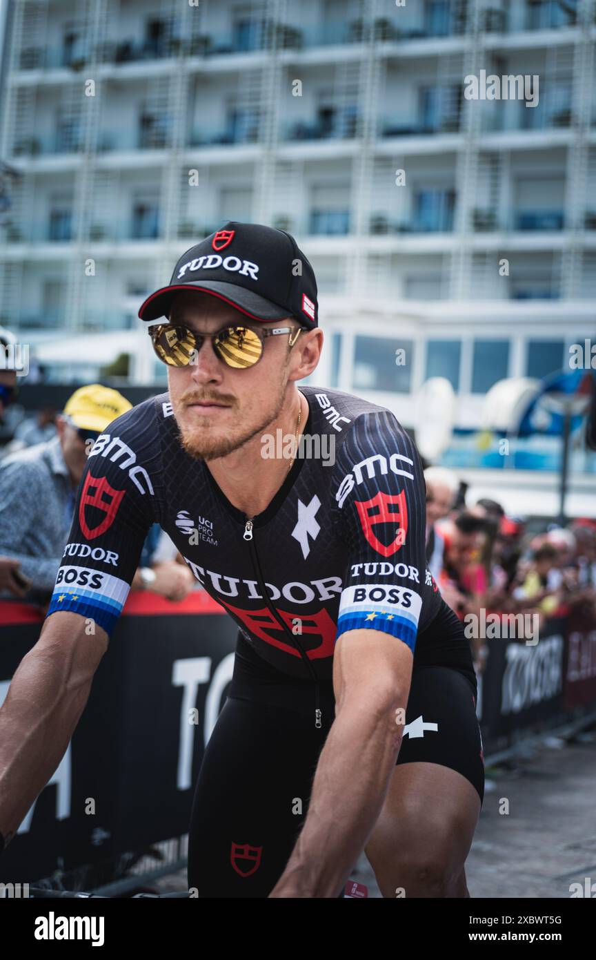 Uno scatto verticale di Matteo Trentin in bicicletta su una strada urbana con gli spettatori al giro d'Italia 2024 Foto Stock