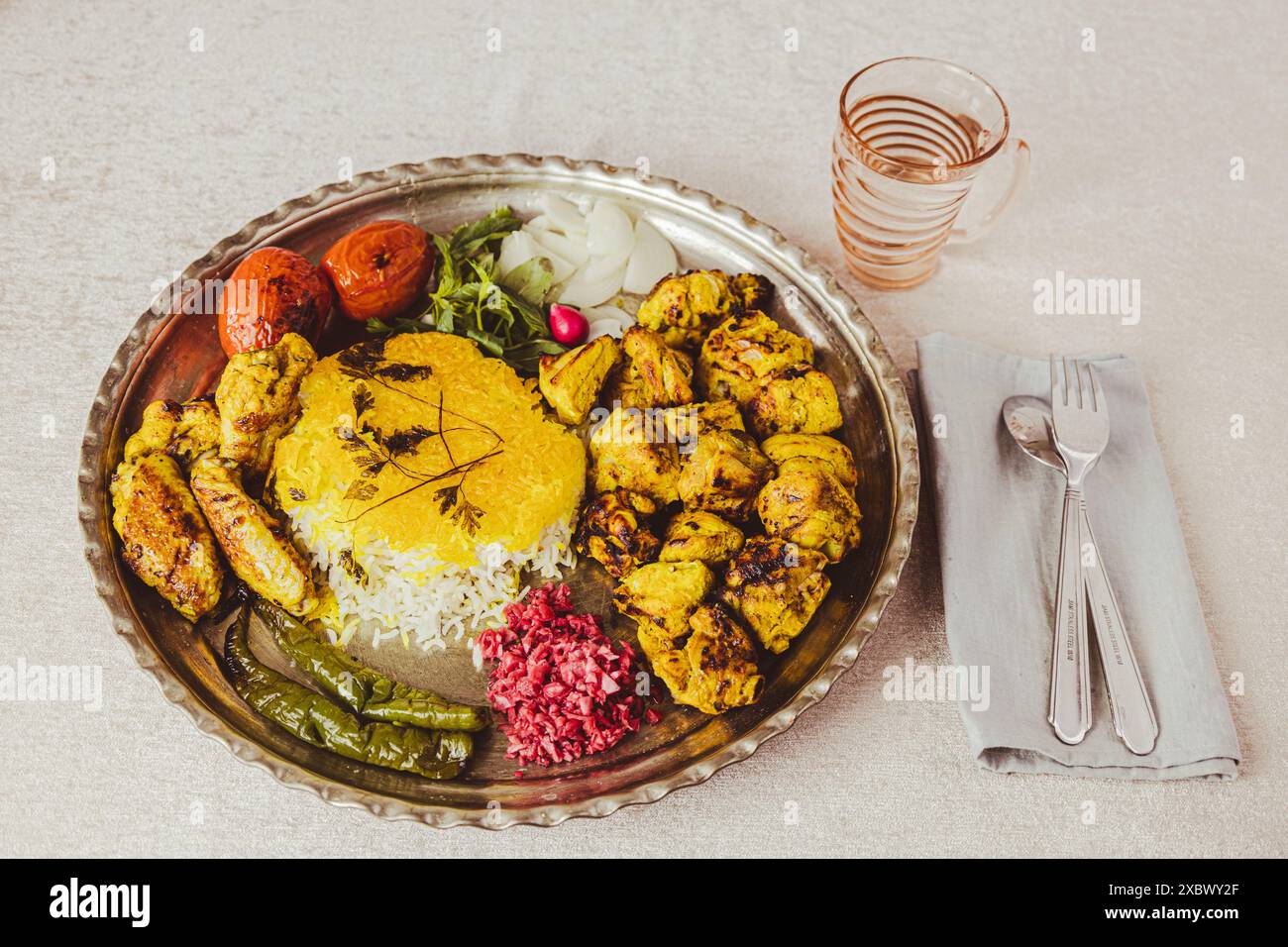 Kebab di pollo iraniano con peperoncino alla griglia e pomodori, riso allo zafferano e verdure su un piatto Foto Stock