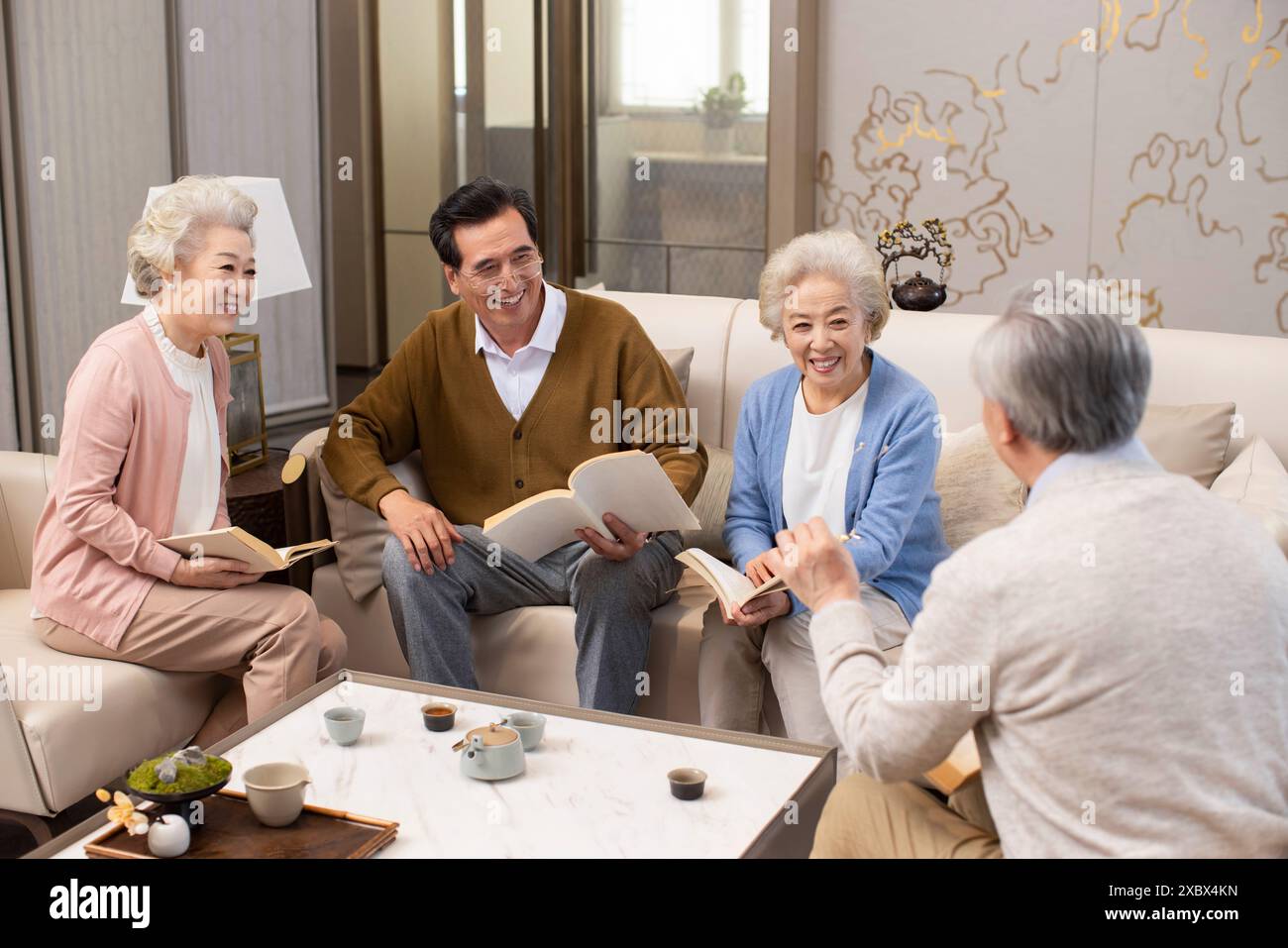 Amici anziani che leggono e discutono libri Foto Stock