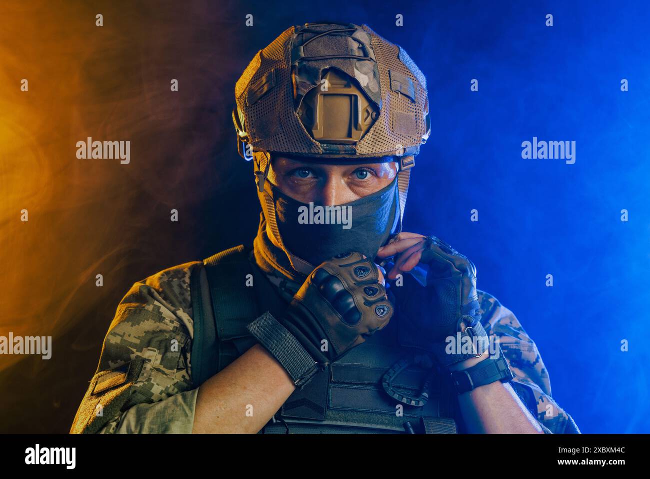 Ritratto di un soldato tattico ucraino in equipaggiamento da combattimento che indossa un casco militare su uno sfondo arancione e blu brillante, conflitto militare Foto Stock