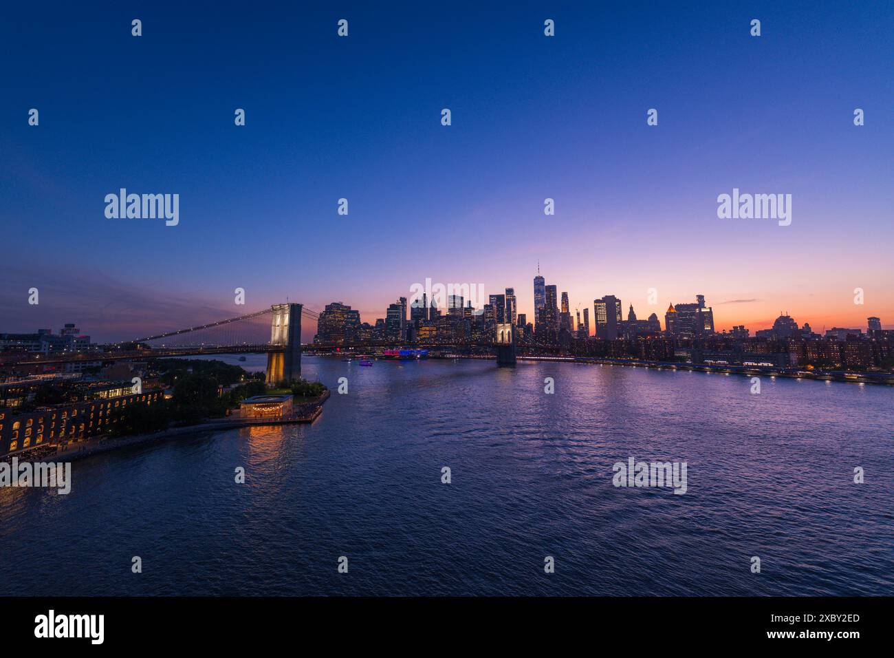 Ponte di Brooklyn e skyline di New York sull'East River sotto un intenso tramonto. Foto Stock