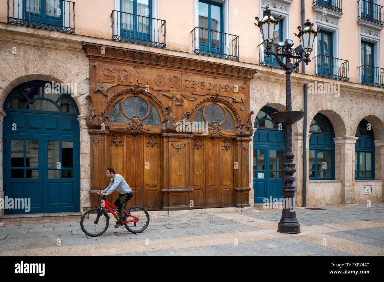 Scena di strada di Burgos - Un ciclista passa davanti alle porte ornate di legno del Salon de Recreo, del Teatro principale, di Burgos, di Castiglia e di León, Spagna. Foto Stock