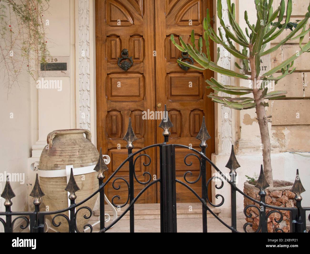 Ingresso tradizionale con porta in legno, pianta, vaso e recinzione metallica, valletta, mediterraneo, malta Foto Stock