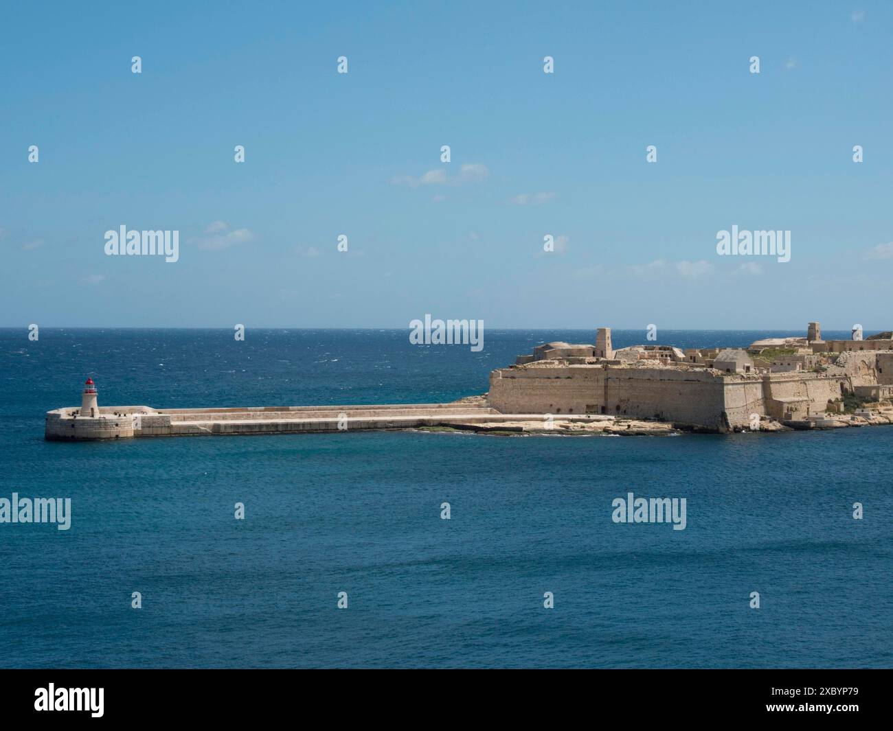 Una storica fortezza in pietra sul mare con un piccolo faro, la valletta, il mediterraneo, malta Foto Stock