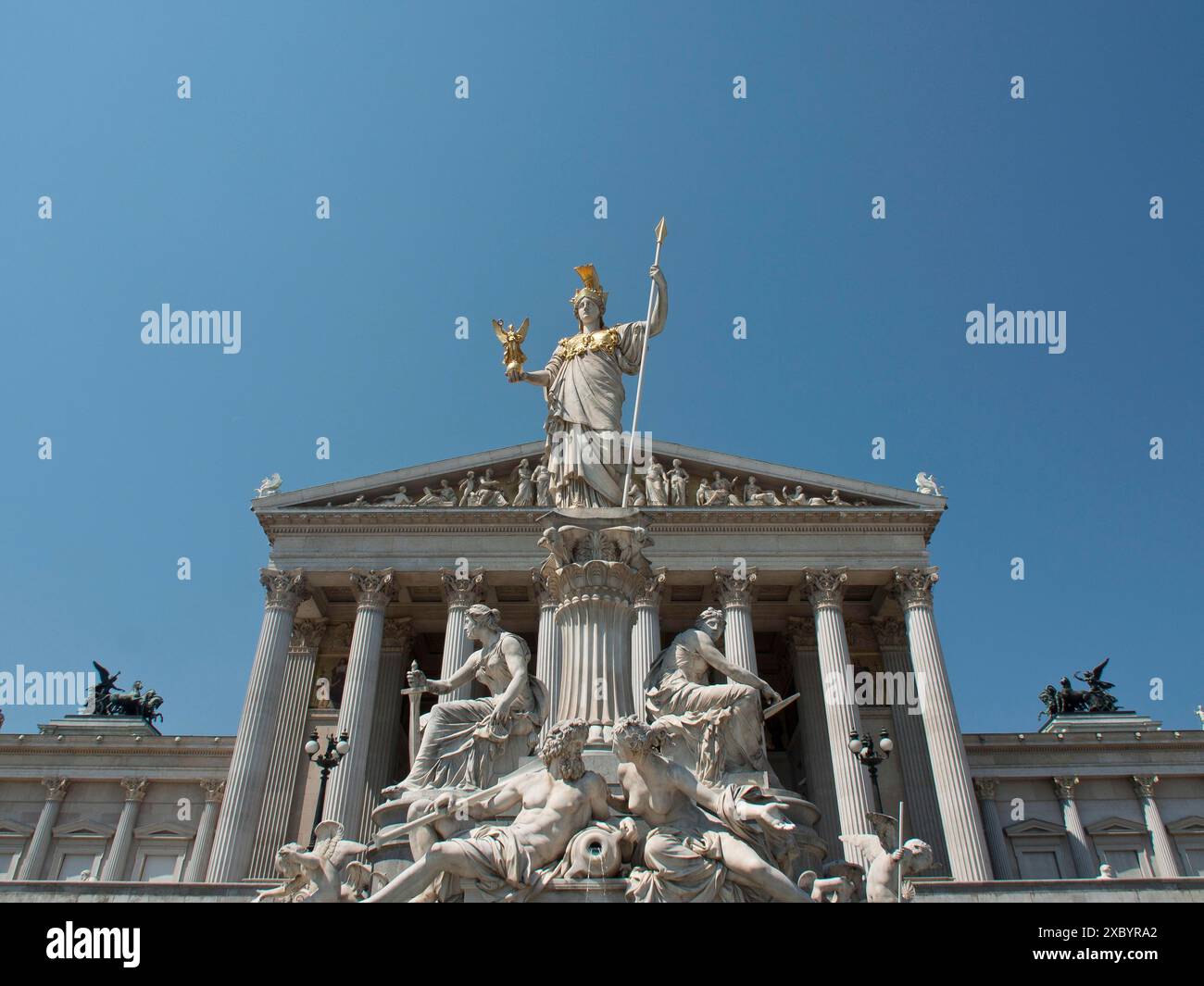 Una magnifica vista di un edificio con una statua di Pallade Atena in cima circondata da antiche sculture sotto un cielo blu, Vienna, Austria Foto Stock