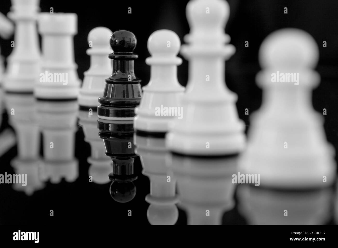 Pedone nero tra scacchi bianchi con riflesso. Il concetto si distingue dalla massa Foto Stock