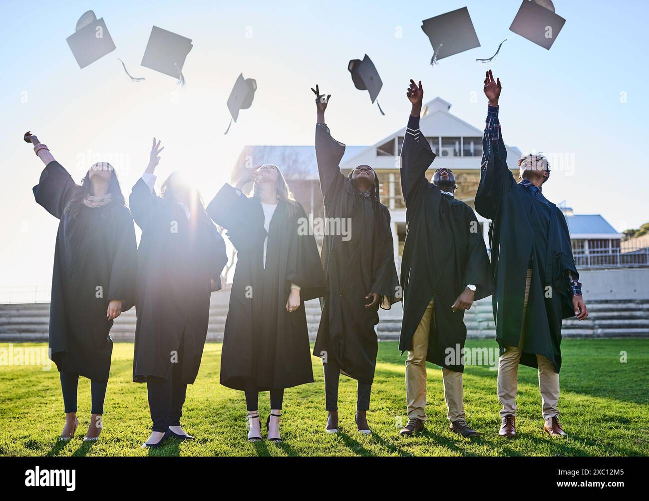 Gettate cappelli, università e amici per la laurea, la cerimonia e il successo accademico all'aperto. College, diversità e uomini e donne felici nel campus Foto Stock
