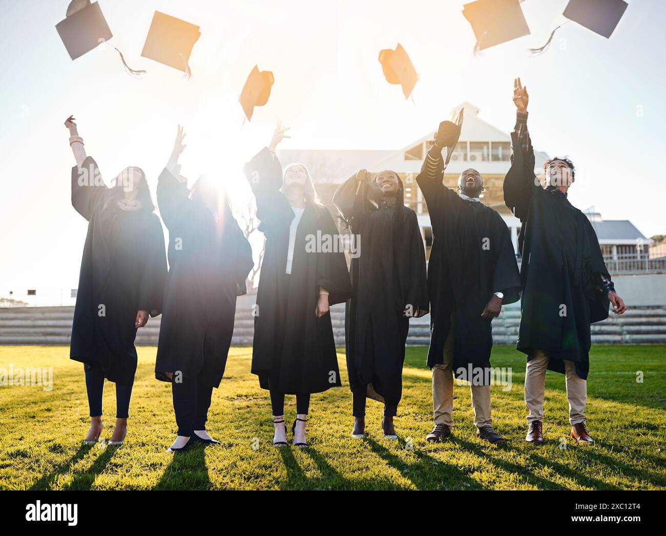 Gettate cappelli, università e studenti per la laurea, la cerimonia e il successo accademico all'aperto. College, diversità e uomini e donne felici nel campus Foto Stock