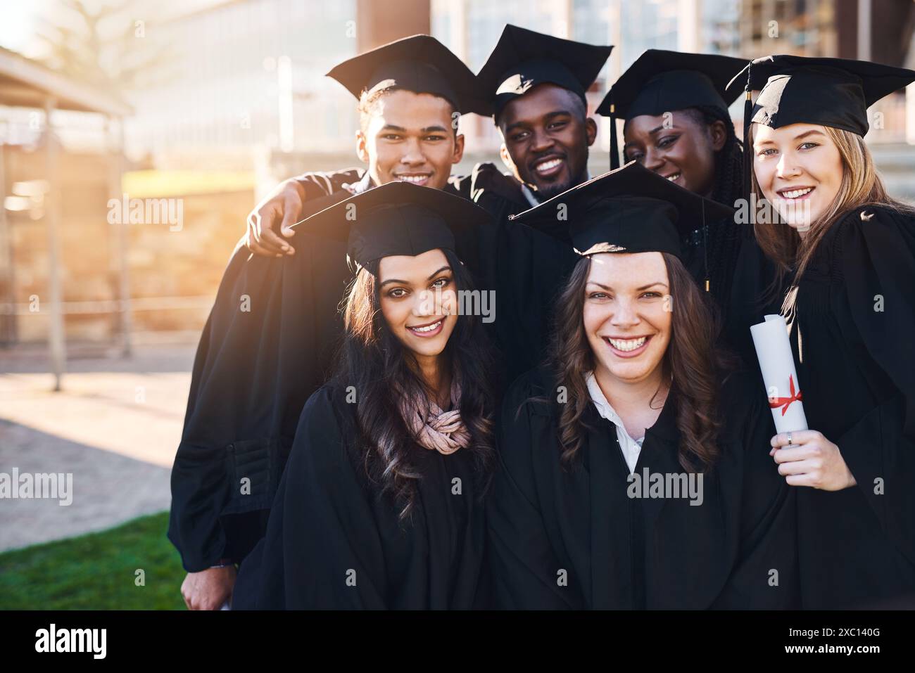 Studenti, università e ritratto di amici per la laurea, la cerimonia e il successo accademico. College, diversità e uomini e donne felici nel campus Foto Stock