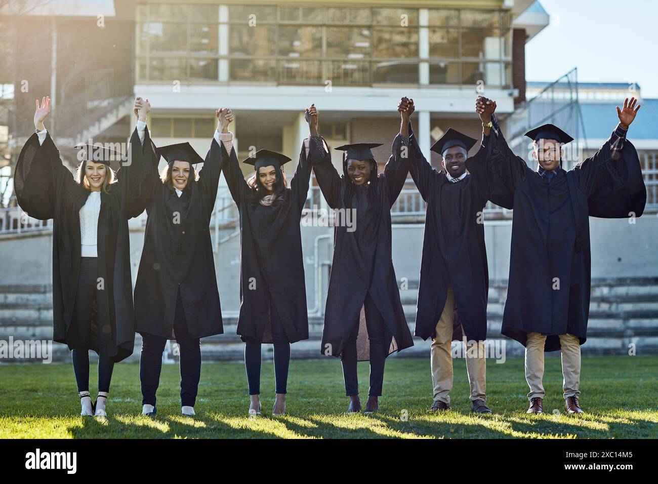 Tenersi per mano, università e ritratti degli studenti per la laurea, la cerimonia e il successo accademico. College, diversità e uomini e donne nel campus Foto Stock