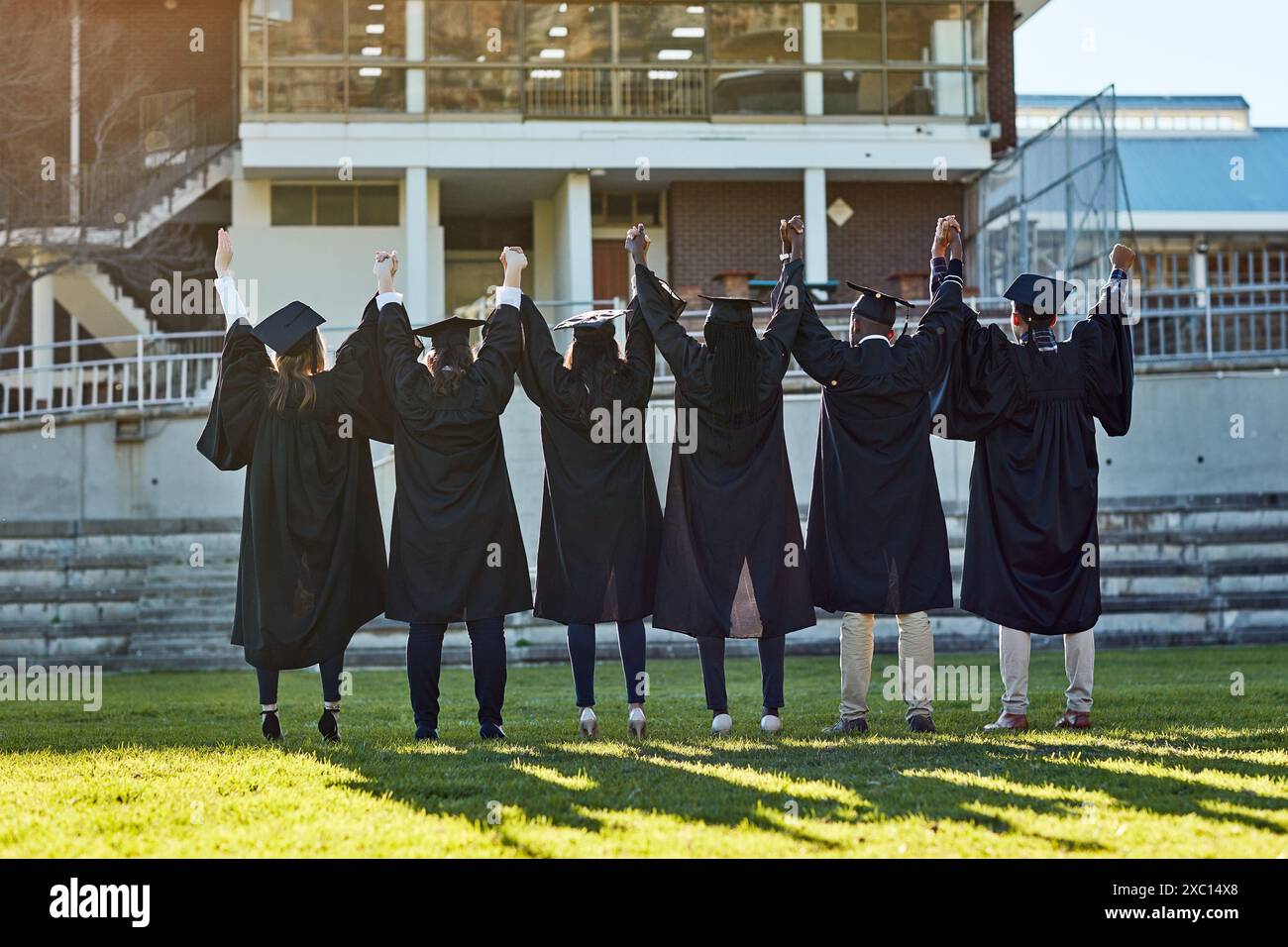 Tenersi per mano, per l'università e dietro gli amici per la laurea, la cerimonia e il successo accademico. College, diversità e uomini e donne nel campus Foto Stock
