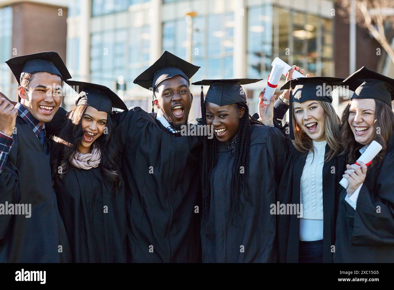 Eccitato, università e ritratto degli amici per la laurea, la cerimonia e il successo accademico. College, diversità e uomini e donne felici nel campus Foto Stock