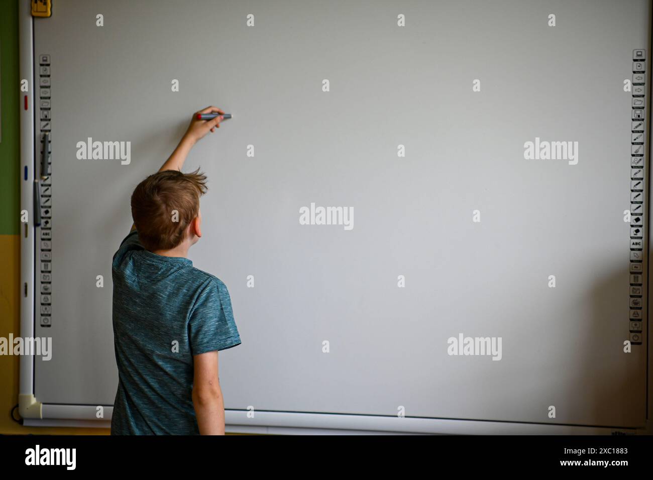 Lo scolaro sta scrivendo su una lavagna vuota in un'aula Foto Stock