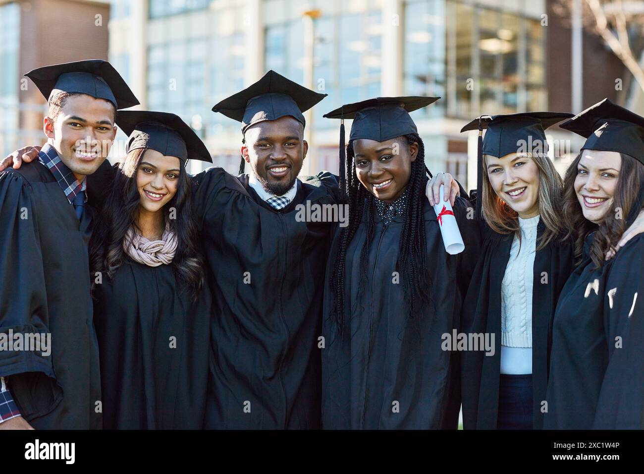 Abbraccio, università e ritratto degli amici per la laurea, la cerimonia e il successo accademico. College, diversità e uomini e donne felici nel campus Foto Stock