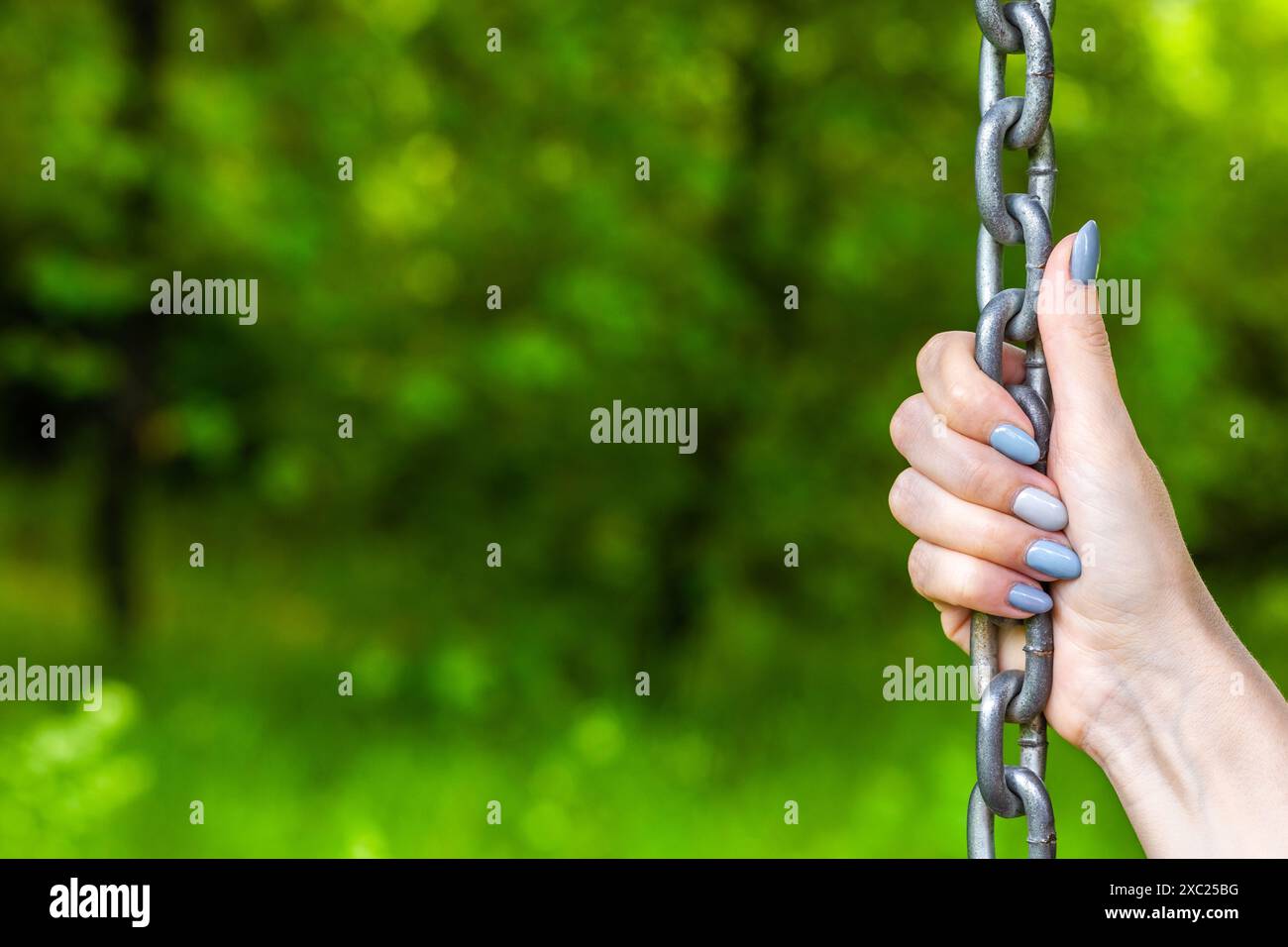 mano femminile che tiene una catena metallica, primo piano. mano che regge una catena metallica. supporto affidabile. un carattere forte Foto Stock