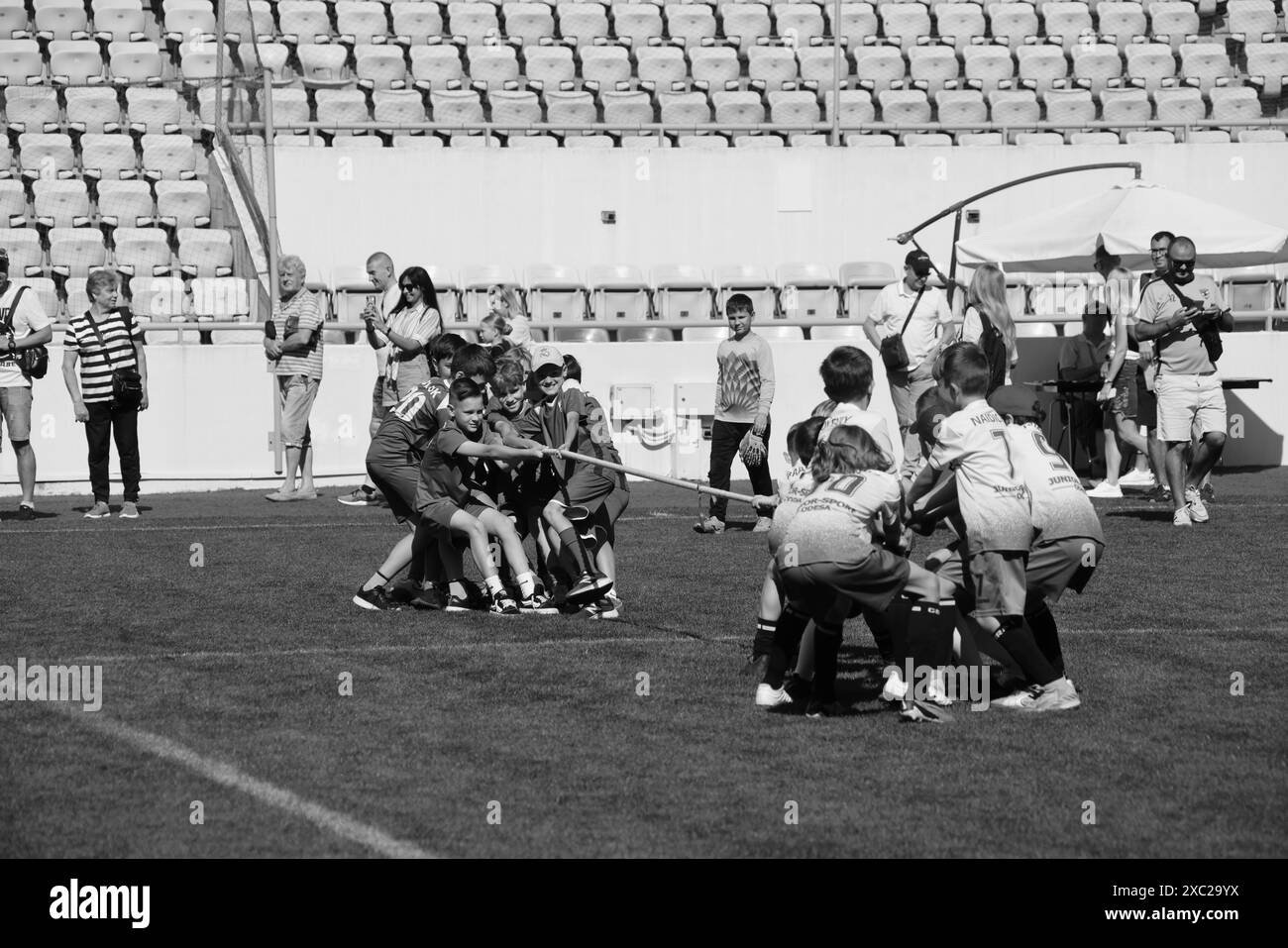 ODESSA, UCRAINA, 9 giugno 2024: Squadre per bambini giocano a tiro di guerra al festival sportivo. Lotta di squadra sportiva - tiro alla fune sull'erba verde del prato dello stadio. Chi Foto Stock