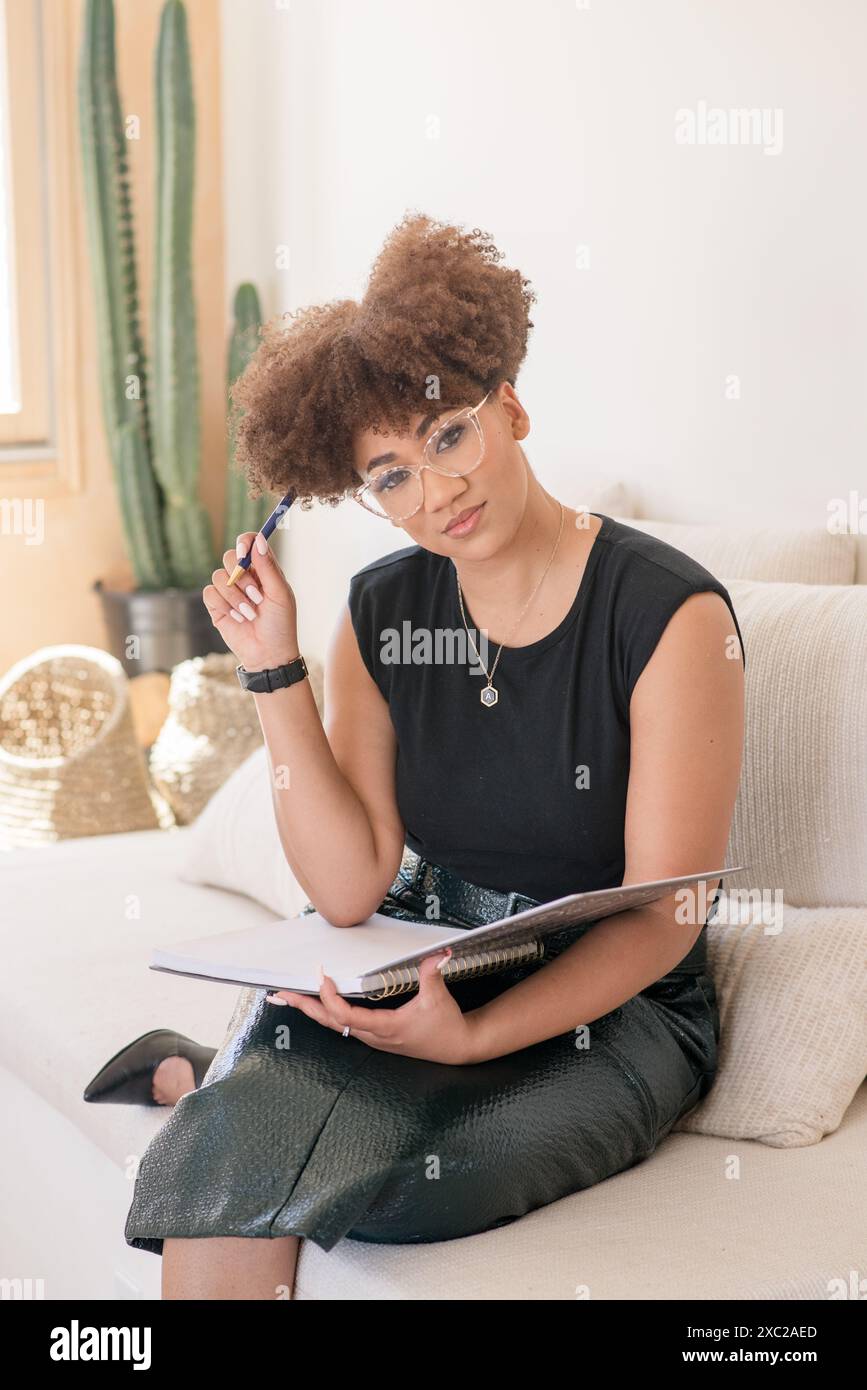 Donne afroamericane con afro seduto sul divano con un notebook Foto Stock