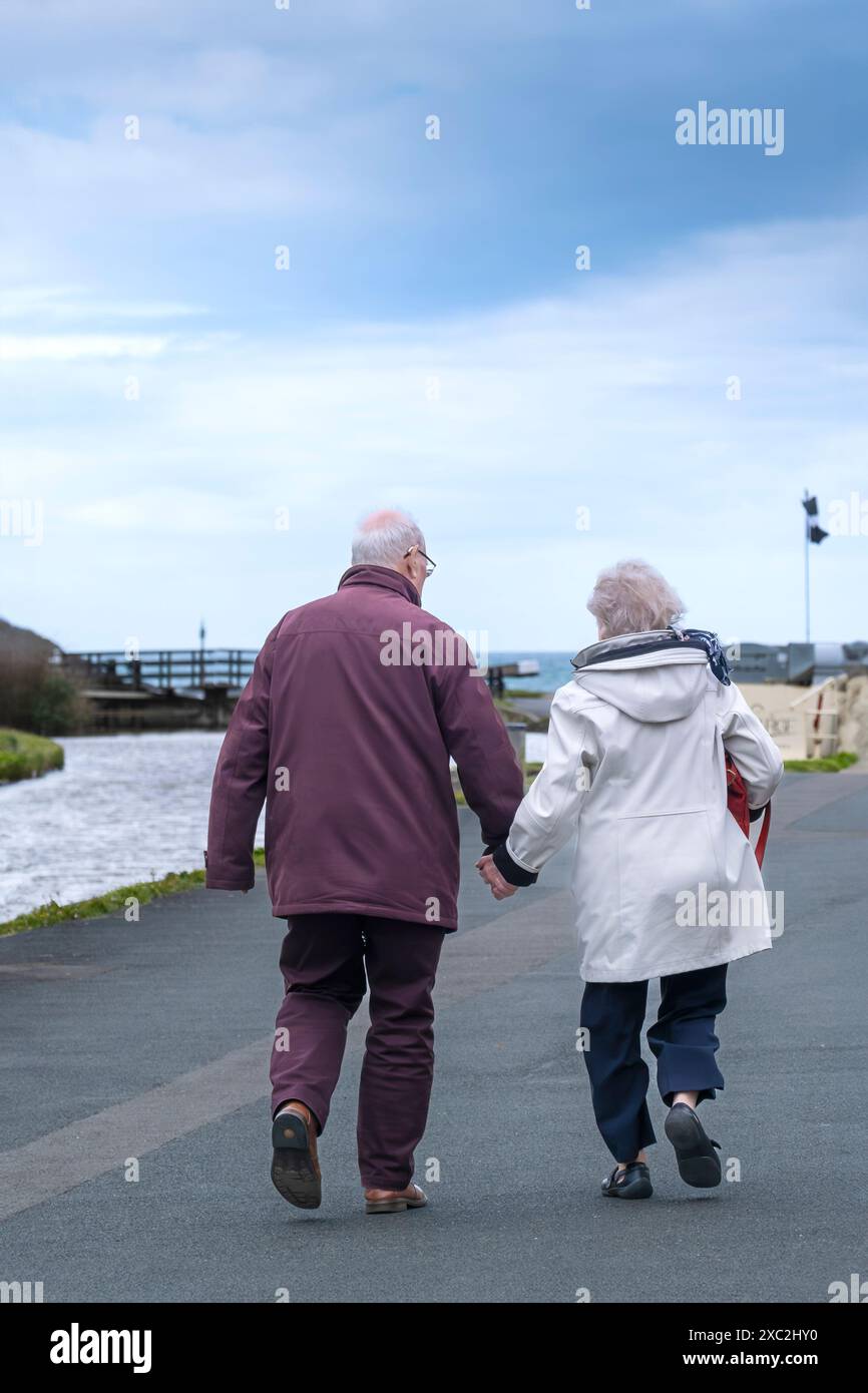 Una coppia anziana di età matura che cammina mano nella mano lungo le rive dello storico canale di Bude sulla costa di Bude in Cornovaglia nel Regno Unito. Foto Stock