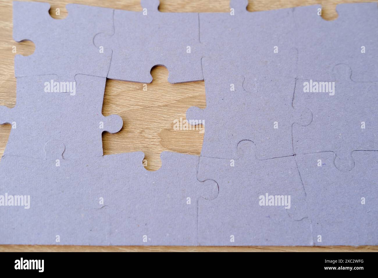 Frammento di puzzle in cartone ripiegato e pile di elementi puzzle non pettinati sullo sfondo, istruzione e apprendimento, miglioramento della memoria Foto Stock