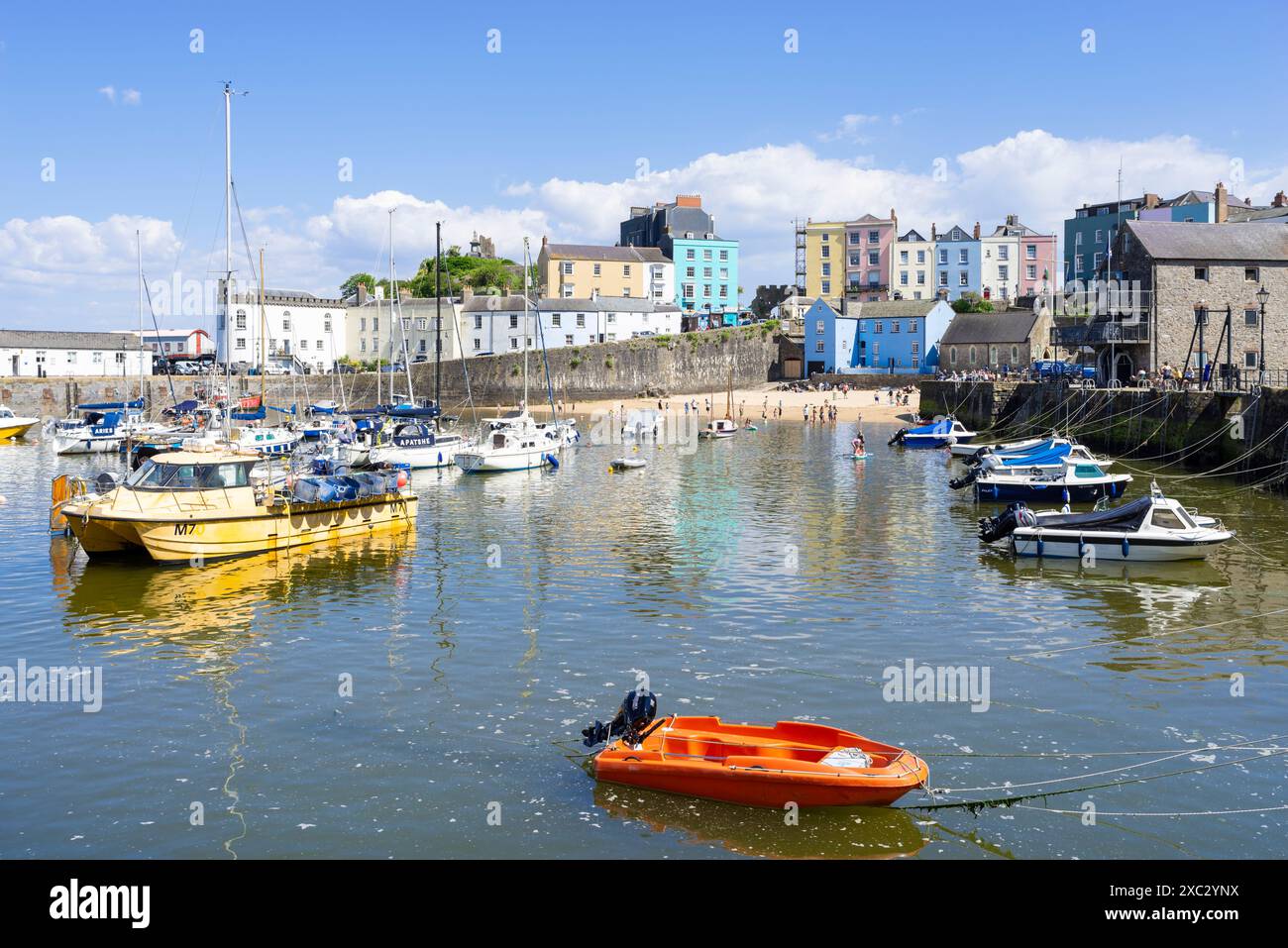 Piccole barche nel porto di Tenby e la spiaggia di Tenby Harbour in alta marea con le case colorate Tenby baia di Carmarthan Pembrokeshire Galles occidentale Regno Unito Foto Stock