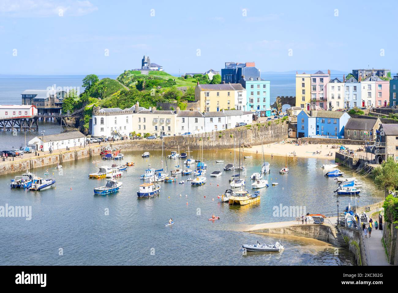 Piccole barche nel porto di Tenby e la spiaggia di Tenby Harbour in alta marea con le case colorate Tenby baia di Carmarthan Pembrokeshire Galles occidentale Regno Unito Foto Stock