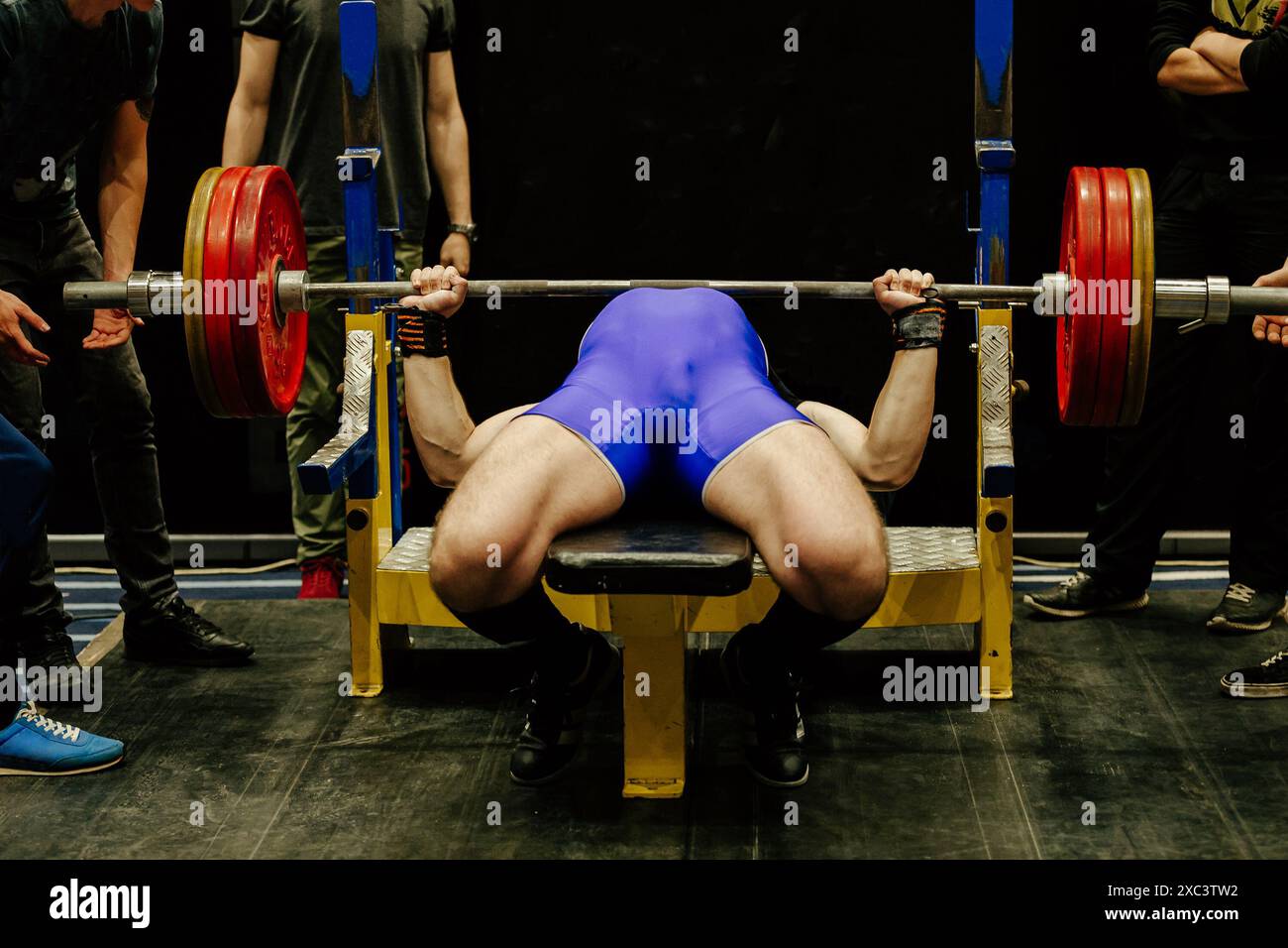 l'atleta uomo esegue una pressa da panca circondata da assistenti Foto Stock