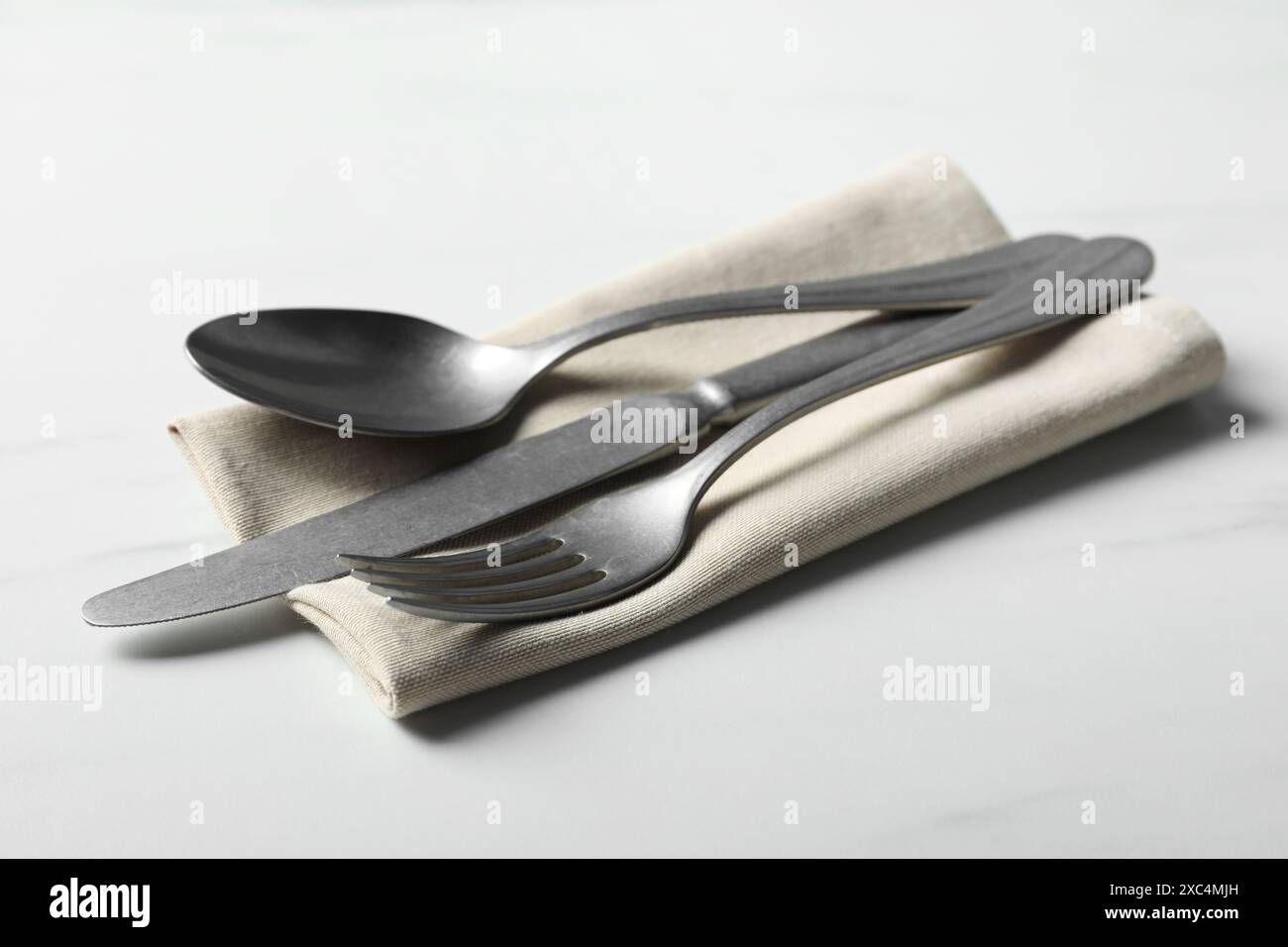 Posate eleganti e tovagliolo su tavolo bianco Foto Stock