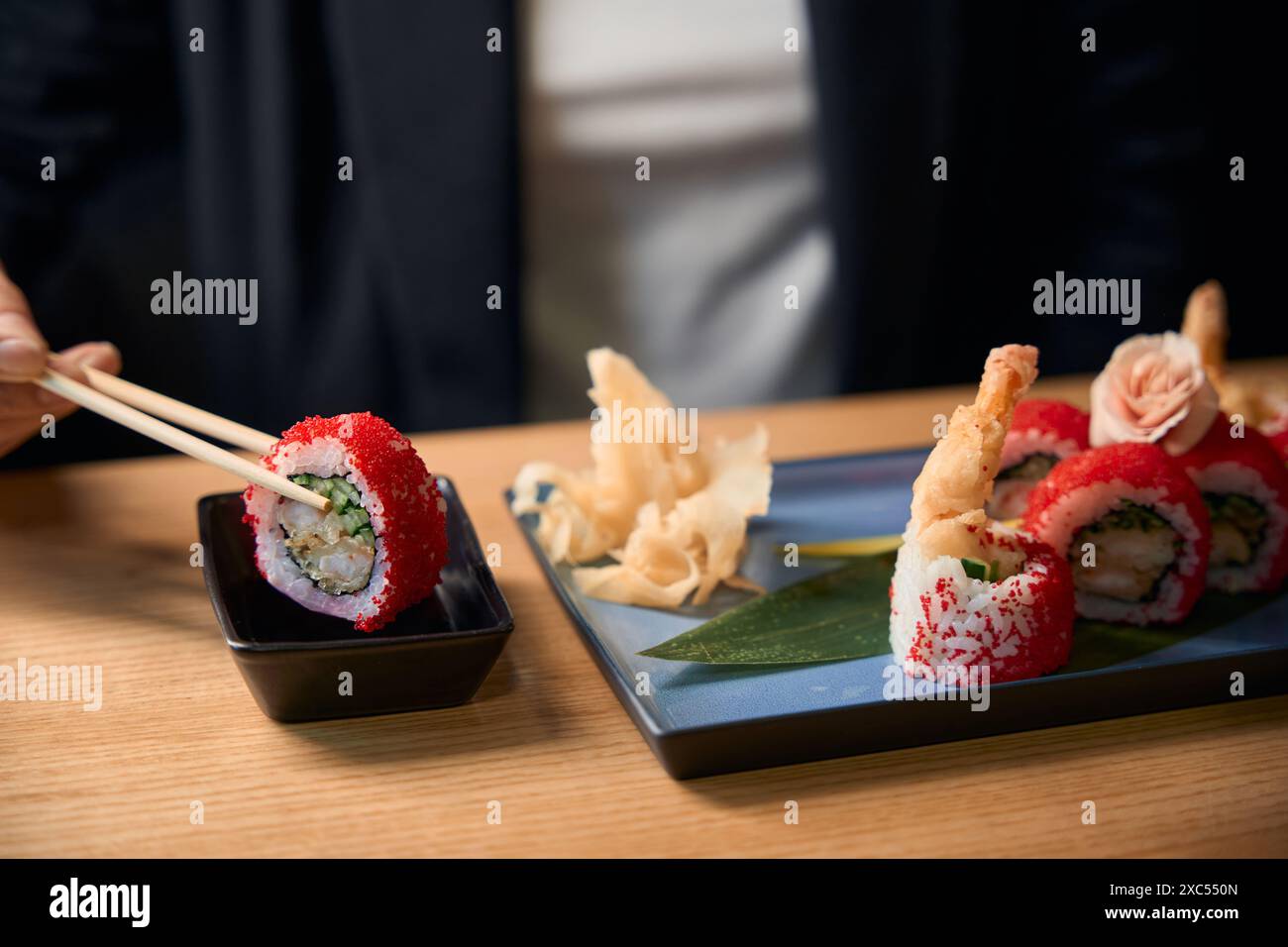 Primo piano donna che immerge il rotolo di tobiko nella salsa di soia Foto Stock
