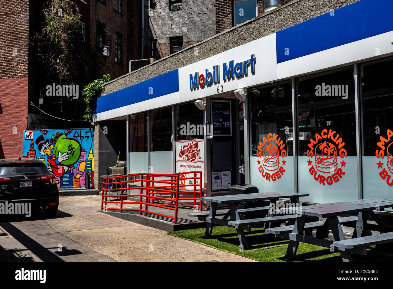 Mobil Mart, stazione di servizio e murale con Donald Duck che tiene in mano il sacco dei soldi, Greenwich Village, Manhattan sotto la 14th Street, New York, NY 10011 Foto Stock