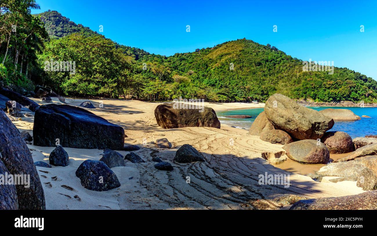 Foresta, collina, rocce e mare della splendida spiaggia di Indaiauba sulla costa dell'isola di Ilhabela a San Paolo Foto Stock