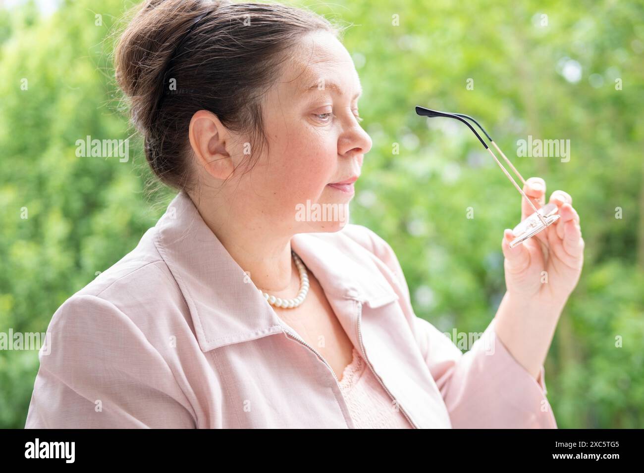 la signora matura guarda attraverso le lenti correttive, lottando contro l'affaticamento visivo, problemi di vista maturi, usura della vista, occhiali correttivi Foto Stock