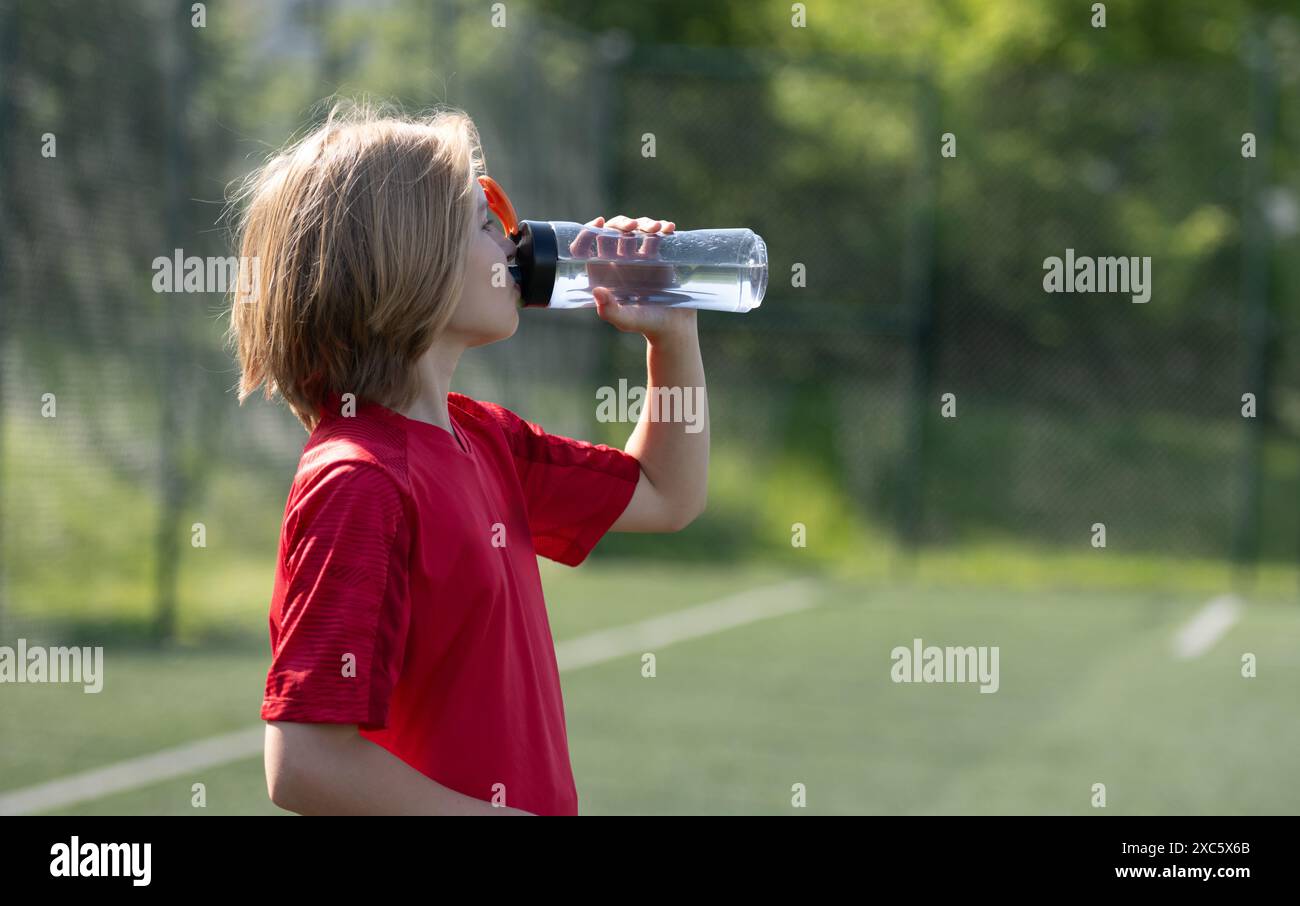 Una ragazza con attrezzatura da calcio beve acqua durante l'allenamento Foto Stock