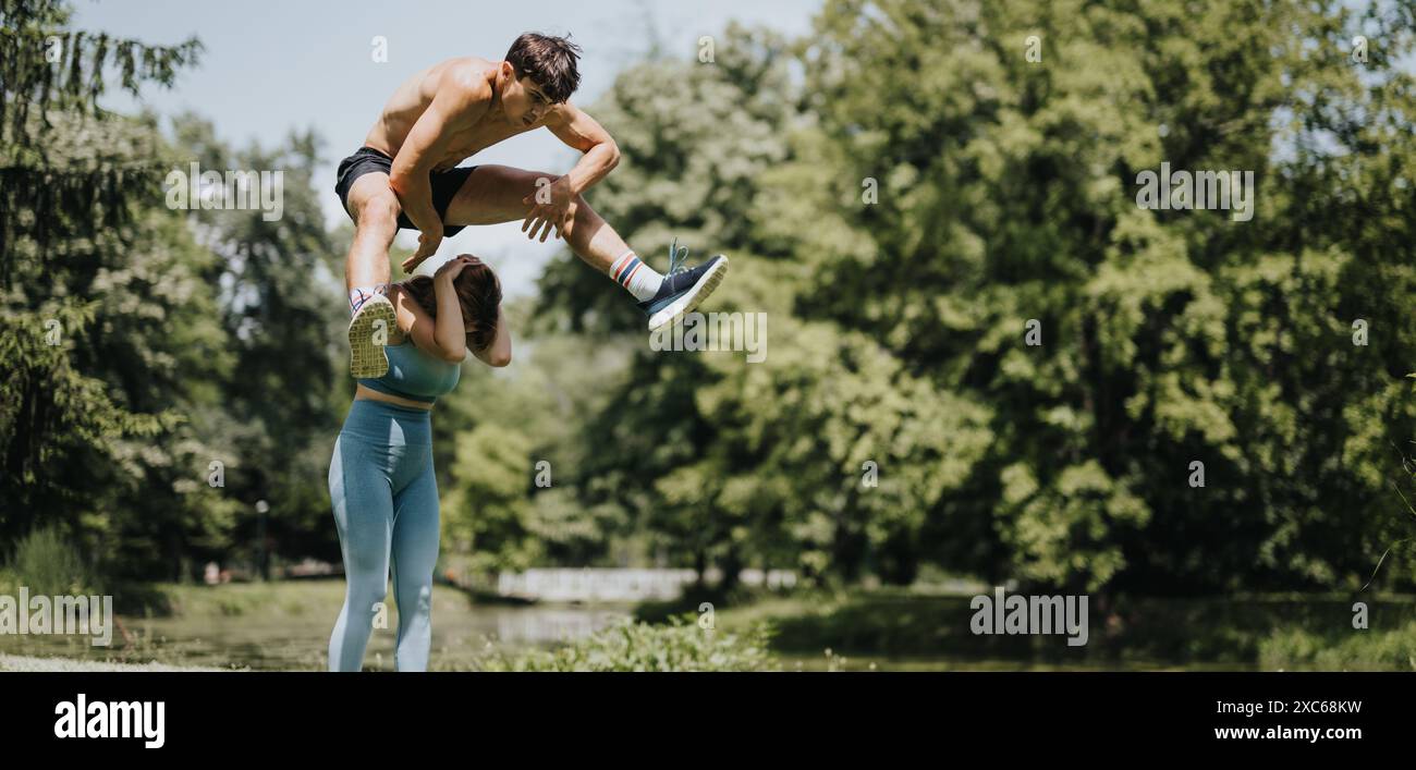 Uomo sportivo flessibile che salta sopra la sua amica al parco Foto Stock