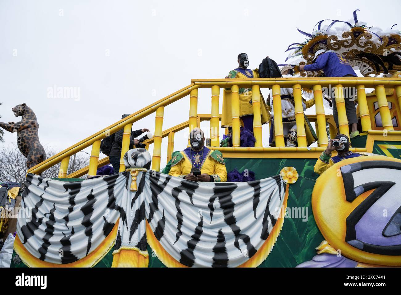 I membri Zulu krewe in elaborati costumi di piume e vernice per il viso si riuniscono fuori da un negozio, preparandosi per la parata annuale del Mardi Gras a New Orleans. Foto Stock