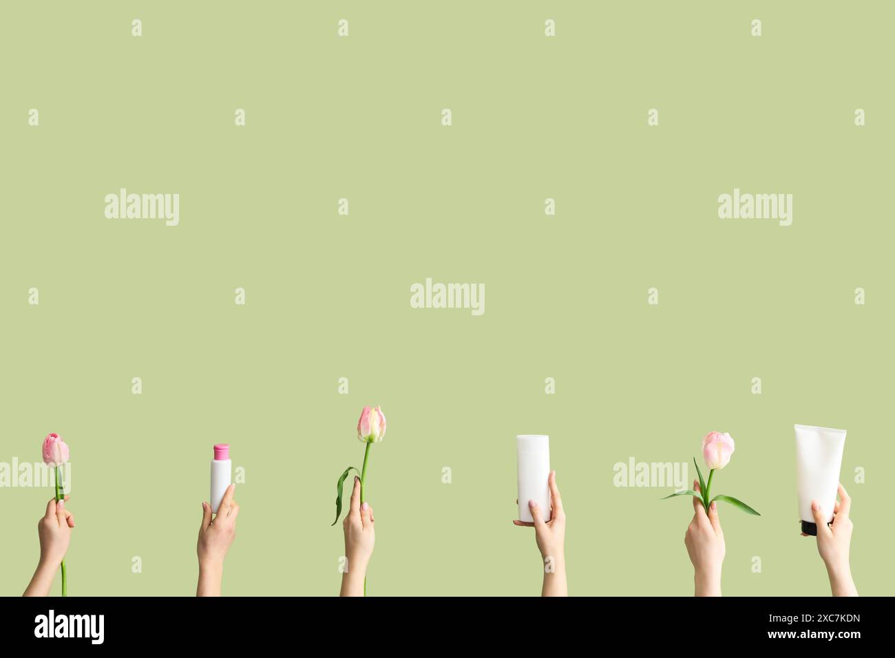 Donne con prodotti cosmetici e tulipani su sfondo verde Foto Stock