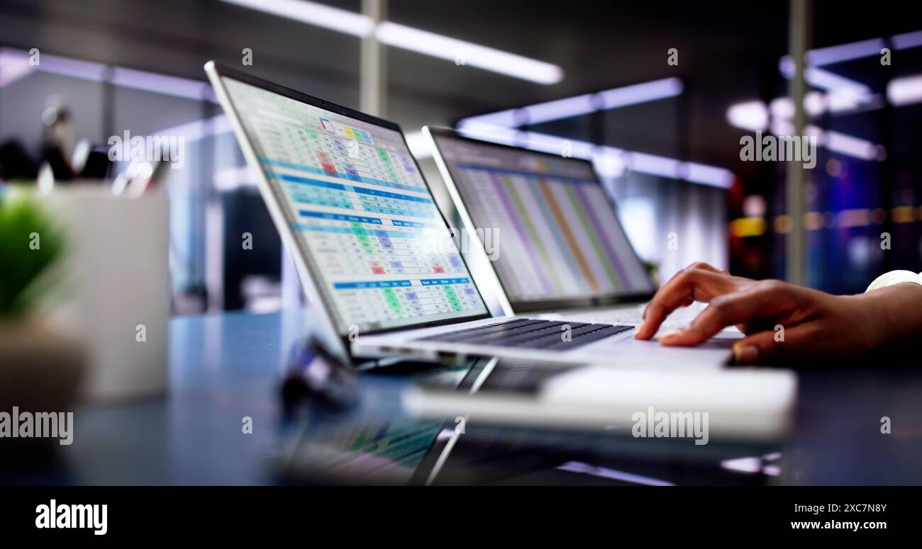 Calcolo di conti medici elettronici e codici in un ufficio nero utilizzando un foglio di calcolo sullo schermo di un computer. Foto Stock