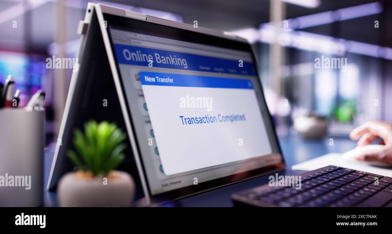 Digital Banking: Imprenditrice afroamericana che utilizza l'autenticazione mobile per il trasferimento finanziario su schermi di notebook e tablet Foto Stock