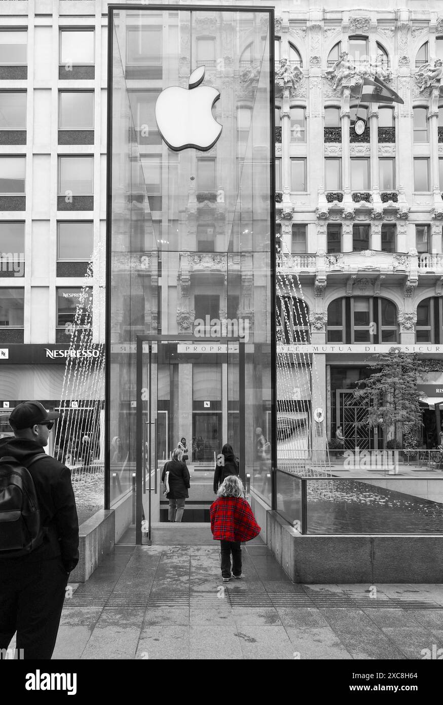 Bianco e nero con colore selettivo. La fontana di cristallo del flagship store Apple in Piazza Liberty, con una bambina da dietro, Milano, Lombardia, Italia Foto Stock